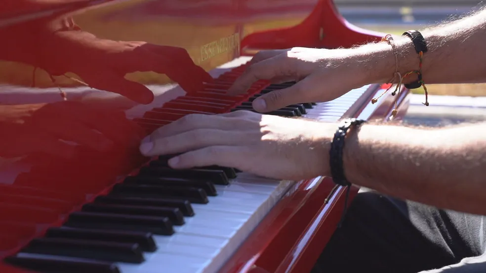 Detalhe das mãos tocando o Piano Bike ao ar livre